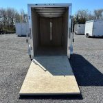 an empty cargo trailer is parked in a gravel lot .