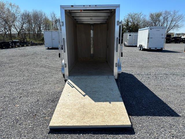 an empty cargo trailer is parked in a gravel lot .