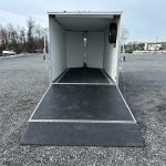 a white trailer is parked in a gravel lot .