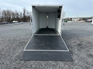 a white trailer is parked in a gravel lot .