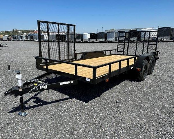 a carry on trailer with a wooden deck is parked in a gravel lot .
