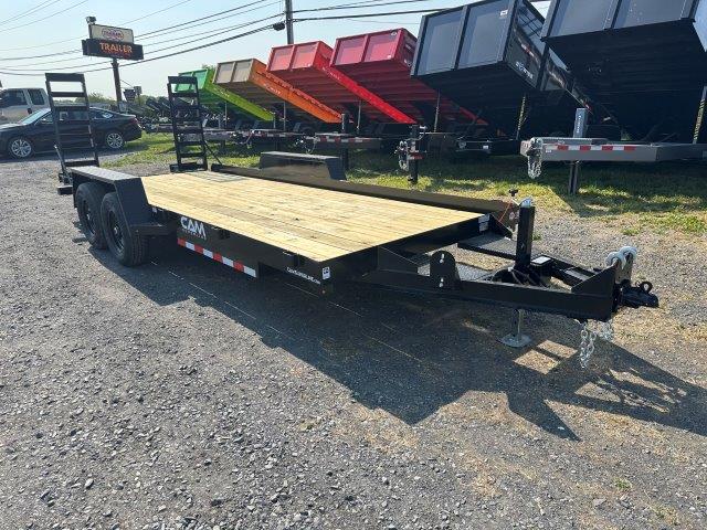 a CAM Superline flatbed trailer with a wooden deck parked next to a row of dump trailers