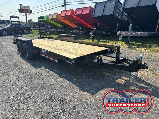 a CAM Superline flatbed trailer with a wooden deck parked next to a row of dump trailers