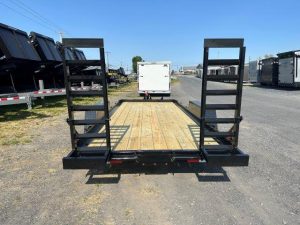 a trailer with a wooden deck is parked on the side of the road .