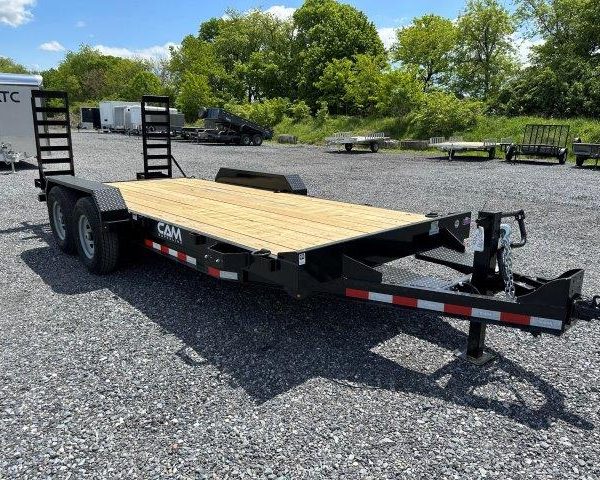 a flatbed trailer is parked in a gravel lot .