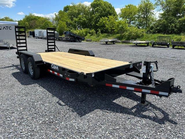 a flatbed trailer is parked in a gravel lot .