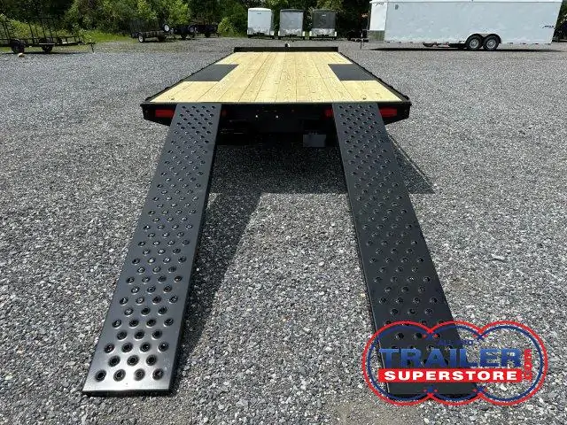 a flatbed trailer with ramps attached to it is parked in a gravel lot