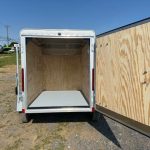 a white trailer with the door open parked on the side of the road