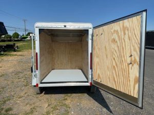 a white trailer with the door open parked on the side of the road