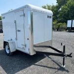 a white trailer is parked in a gravel lot .