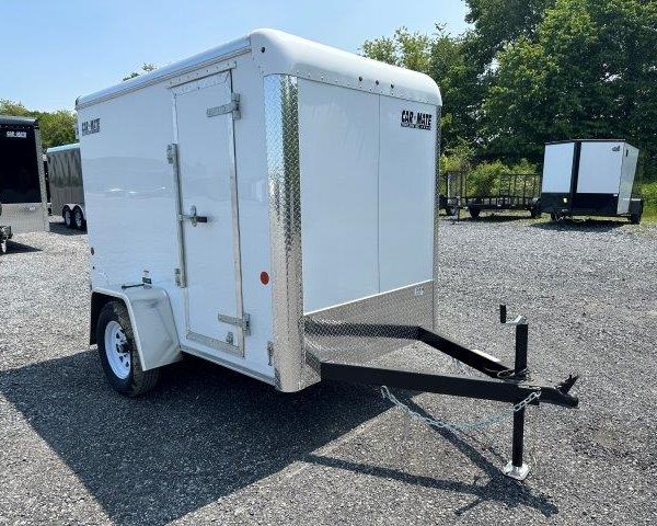 a white trailer is parked in a gravel lot .