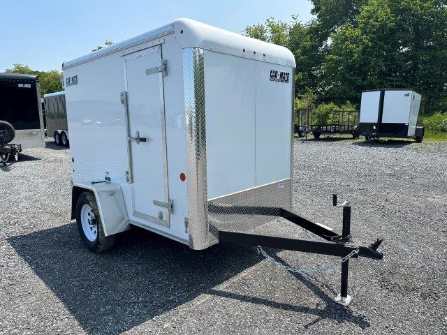 a white trailer is parked in a gravel lot .