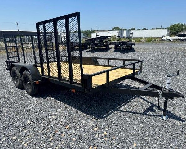 a carry on trailer is sitting on top of a gravel lot .