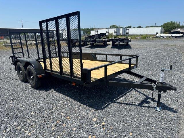 a carry on trailer is sitting on top of a gravel lot .