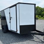 a black and white trailer parked in a gravel lot