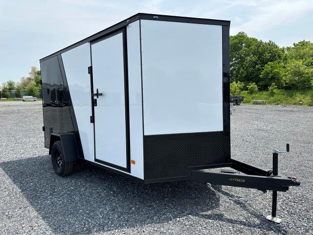 a black and white trailer parked in a gravel lot