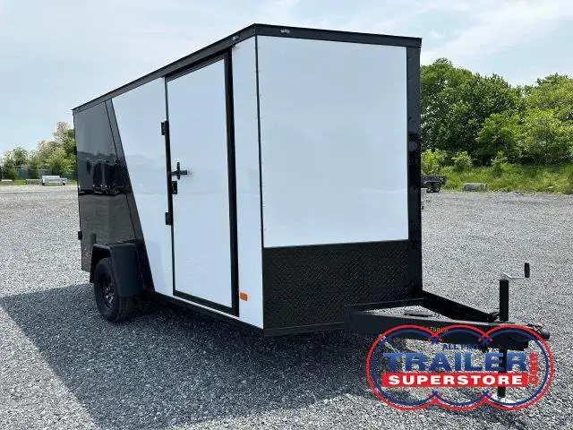 a black and white trailer parked in a gravel lot
