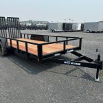 a black trailer with a wooden deck parked in a gravel lot