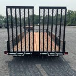 a bwise trailer with a wooden deck parked in a gravel lot .