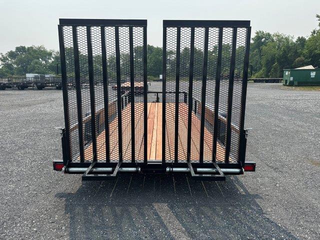 a bwise trailer with a wooden deck parked in a gravel lot .
