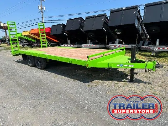 a green trailer is parked in a dirt lot next to a row of dump trailers