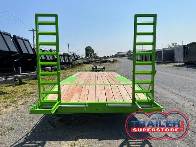 a green trailer with a wooden deck is parked on the side of the road .
