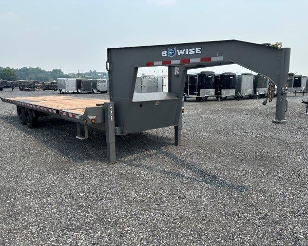 a flatbed trailer is parked in a gravel lot