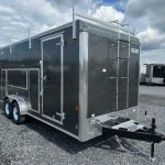 a black trailer with a ladder parked in a gravel lot