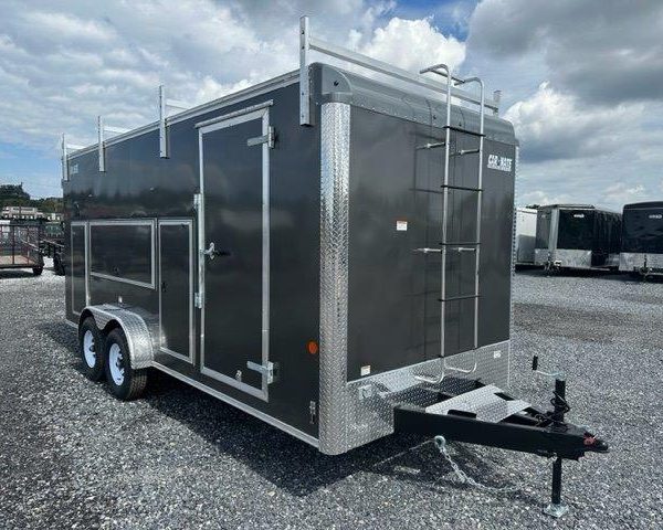 a black trailer with a ladder parked in a gravel lot