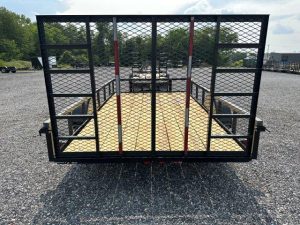 a trailer is parked in a gravel lot with a fence around it .