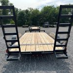 a Carry On trailer with a wooden deck parked in a gravel lot