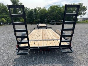 a Carry On trailer with a wooden deck parked in a gravel lot