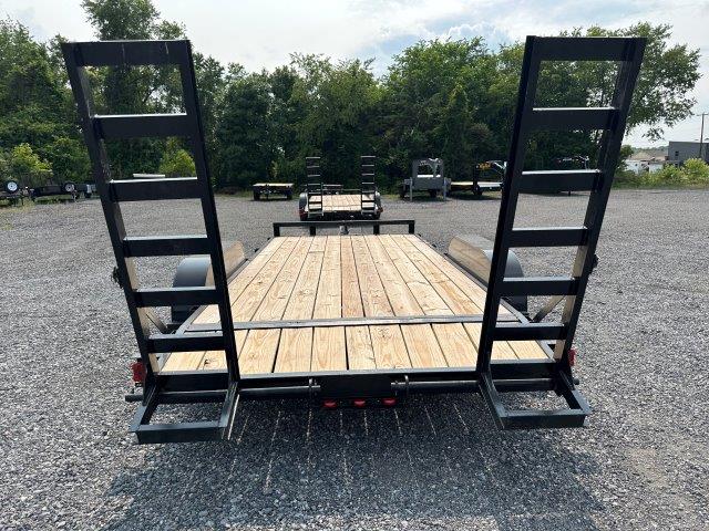 a Carry On trailer with a wooden deck parked in a gravel lot