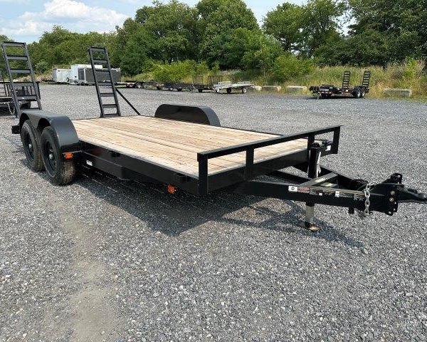 a flatbed trailer is parked in a gravel lot .
