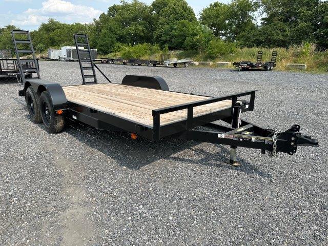 a flatbed trailer is parked in a gravel lot .