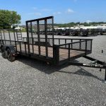 a black trailer is parked in a gravel lot .