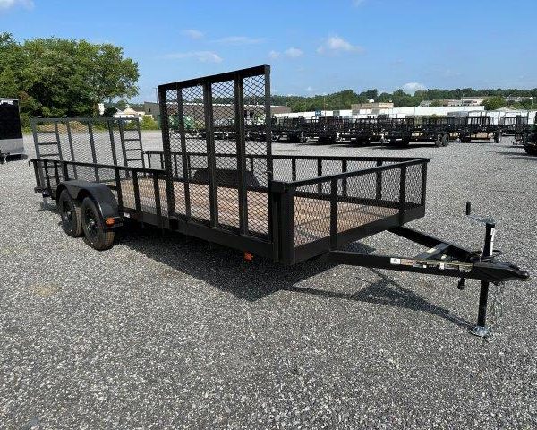a black trailer is parked in a gravel lot .