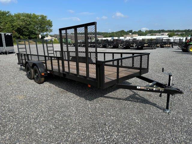 a black trailer is parked in a gravel lot .