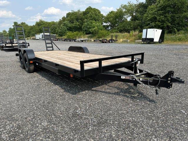 a carry on flatbed trailer is parked in a gravel lot .