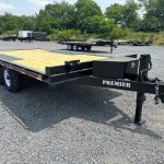 a flatbed trailer is parked in a gravel lot .