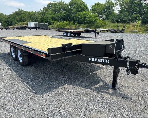 a flatbed trailer is parked in a gravel lot .