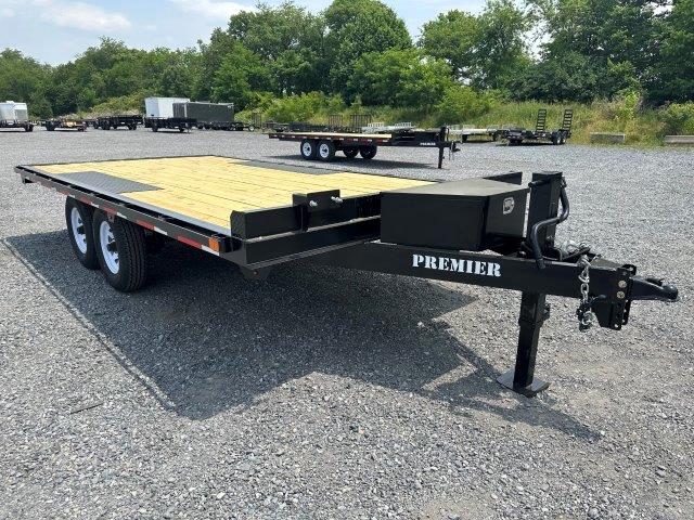 a flatbed trailer is parked in a gravel lot .