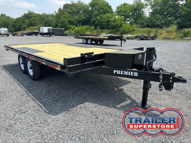 a flatbed trailer is parked in a gravel lot .