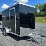a black and silver trailer parked in a gravel lot