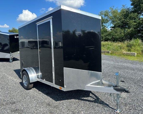 a black and silver trailer parked in a gravel lot