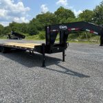 a flatbed trailer is parked in a gravel lot .