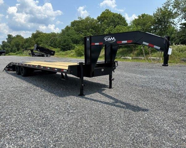 a flatbed trailer is parked in a gravel lot .