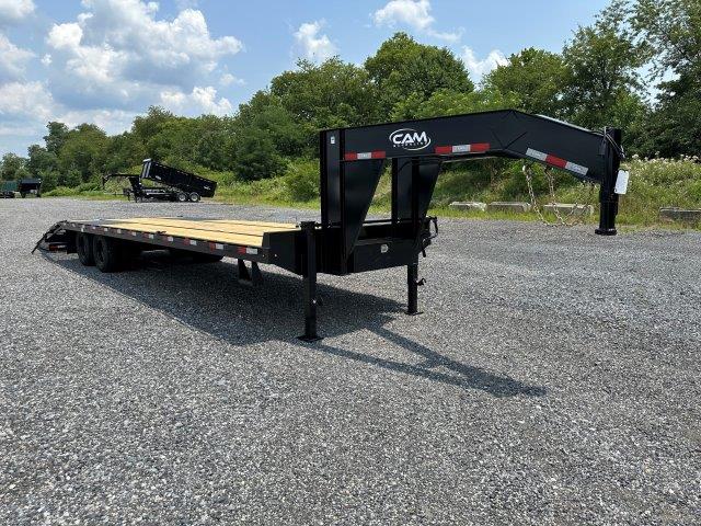 a flatbed trailer is parked in a gravel lot .
