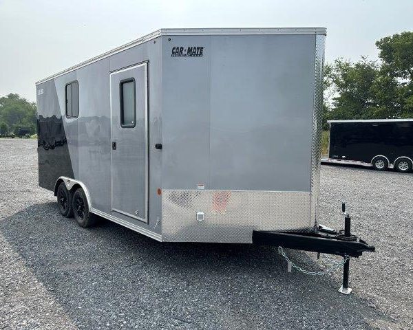 a gray and black trailer is parked in a gravel lot