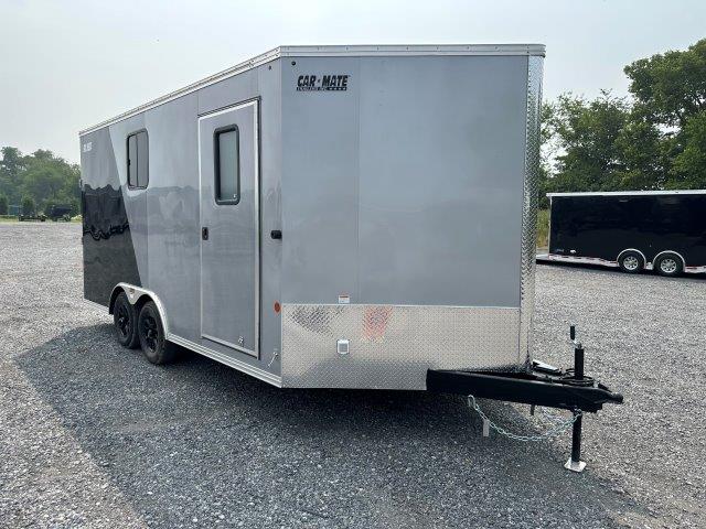 a gray and black trailer is parked in a gravel lot